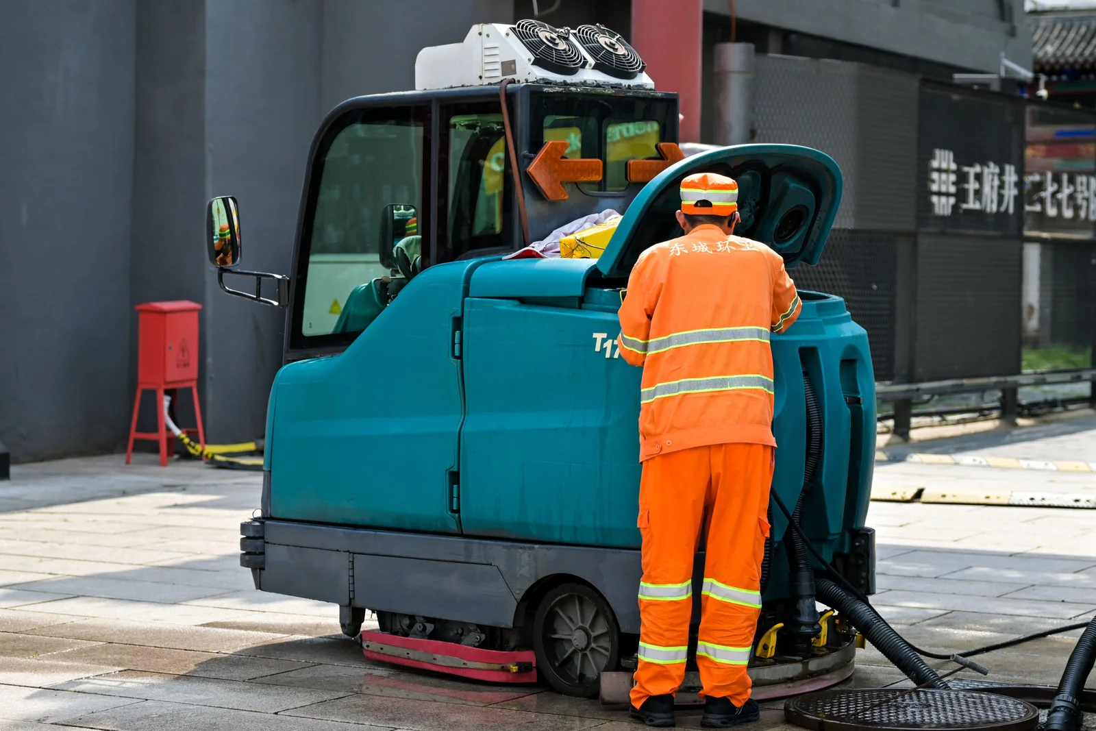 Industrial worker operating a ride-on mechanical floor sweeping and scrubbing machine